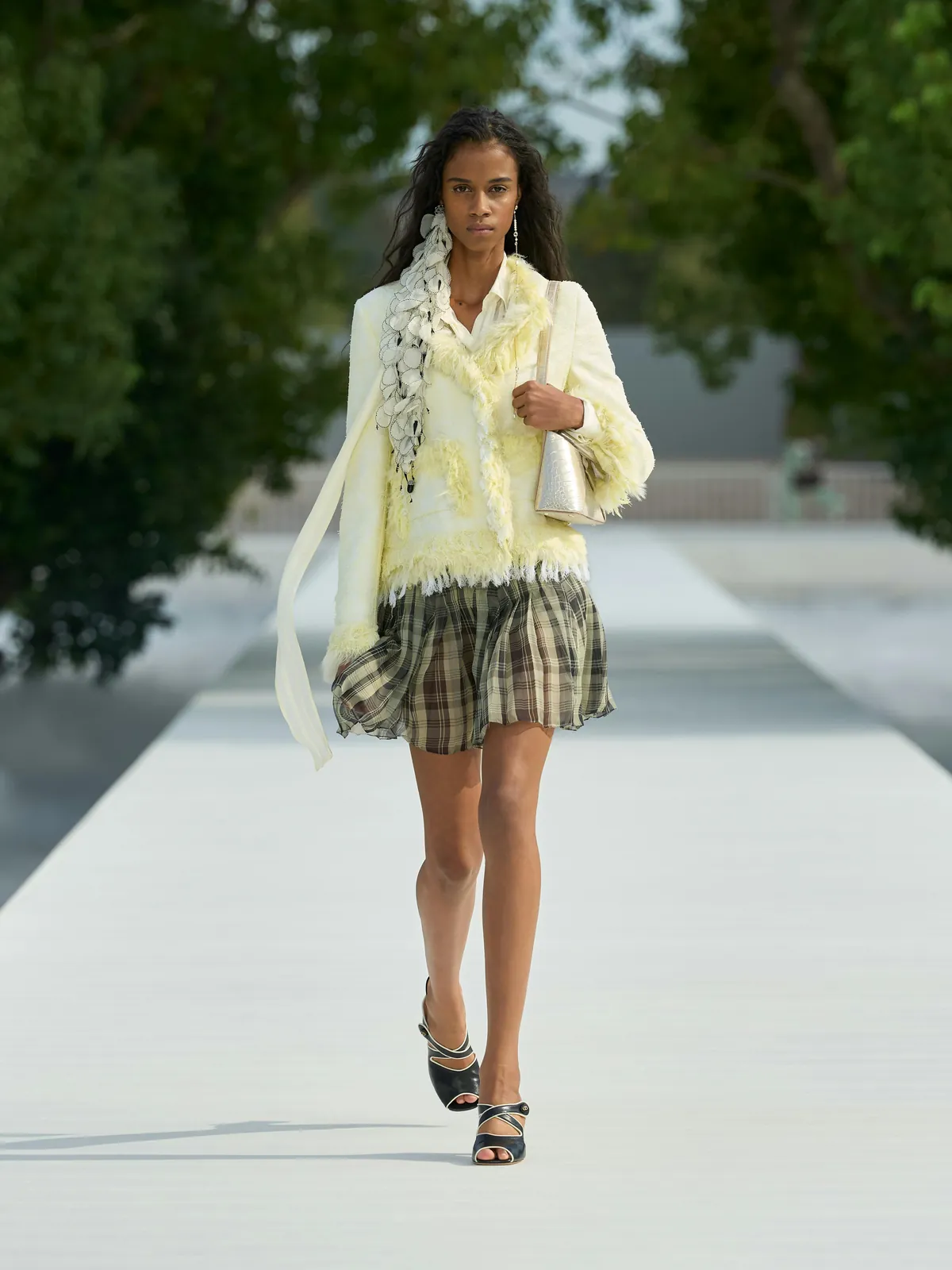 Dior Été 2027 look 3 : veste jaune pâle à franges, écharpe à volants et minijupe à carreaux
